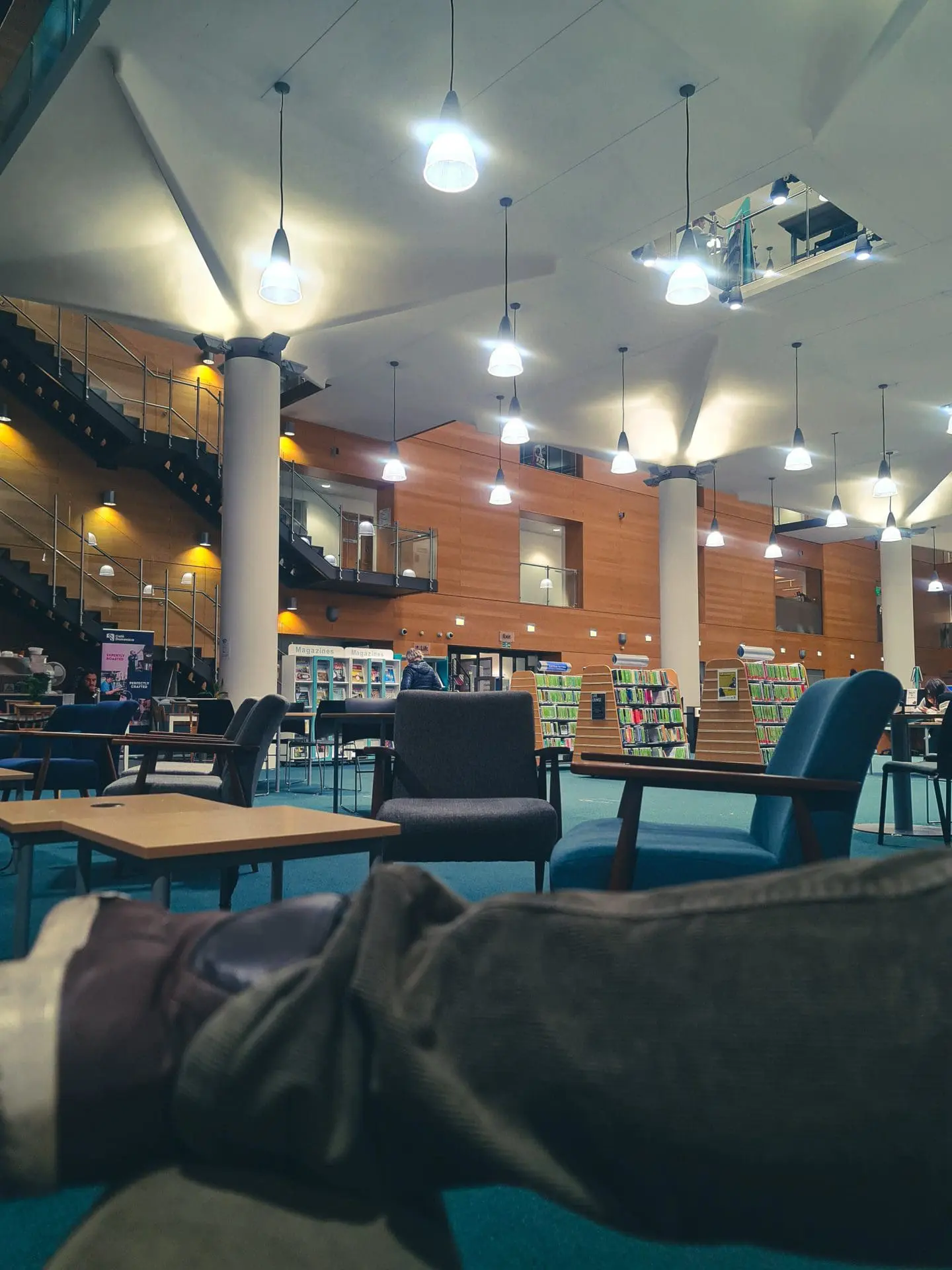 Photo of Interior view of a modern library featuring seating areas and bookshelves. | Wander Sober
