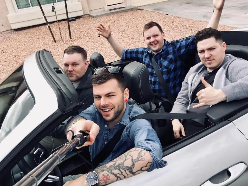 Photo of Four men taking a selfie in a convertible car with the top down. | Wander Sober