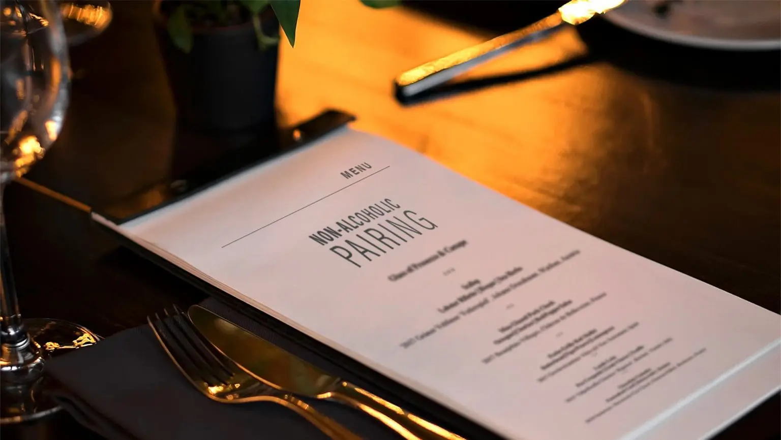 Photo of Menu titled 'Non-Alcoholic Pairing' displayed on a table with cutlery and a plant. | Wander Sober