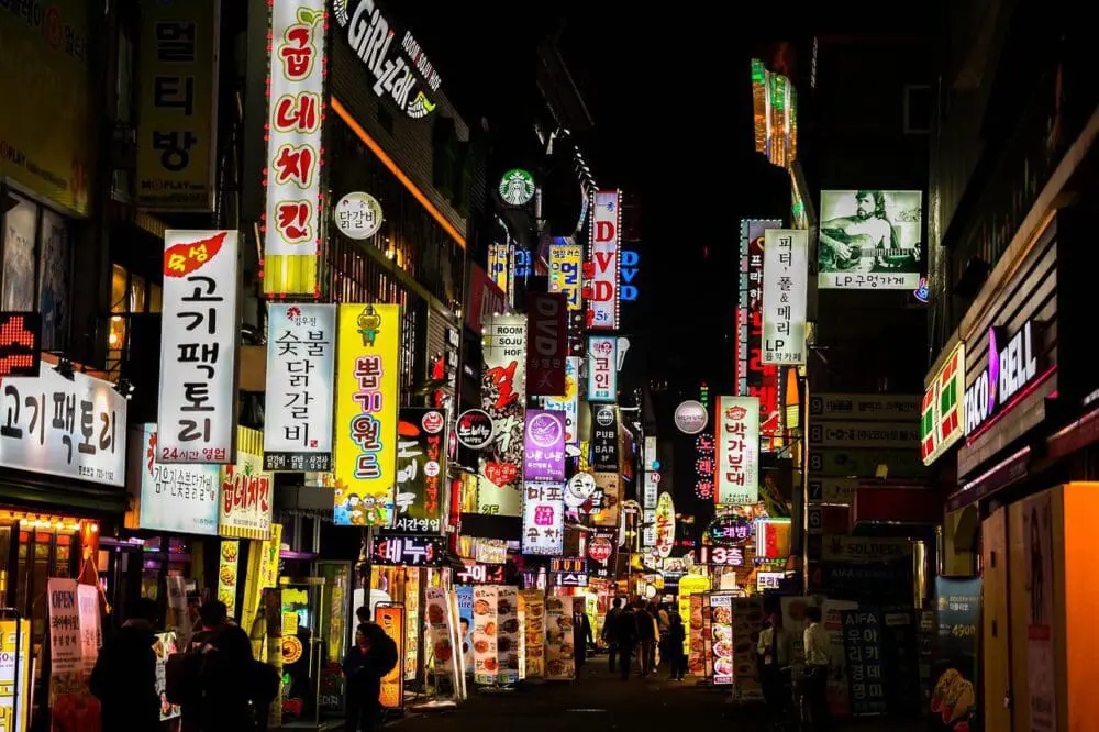 Illuminated neon signs lining a street at night in an urban setting.