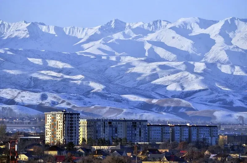 Photo of Snow-covered mountains in the background with urban buildings in the foreground. | Wander Sober