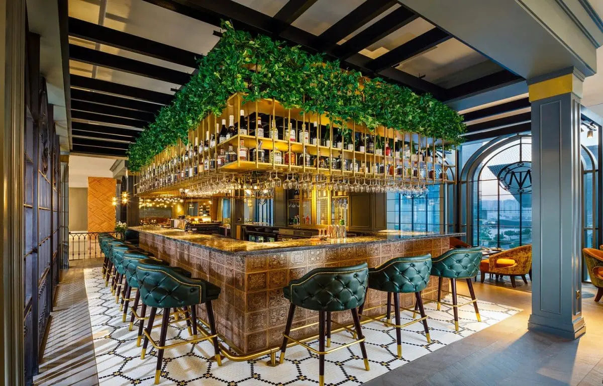 Photo of Interior view of a modern bar featuring a large greenery installation and seating area. | Wander Sober