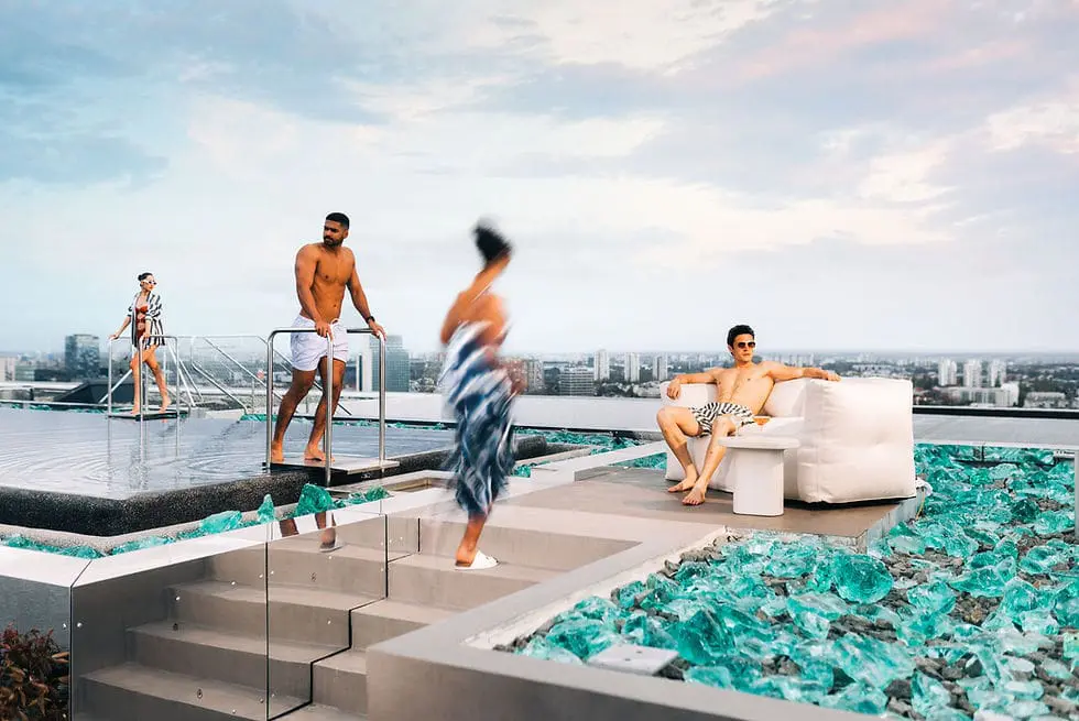 Photo of Group of individuals enjoying a rooftop pool area with modern seating and glass decor. | Wander Sober