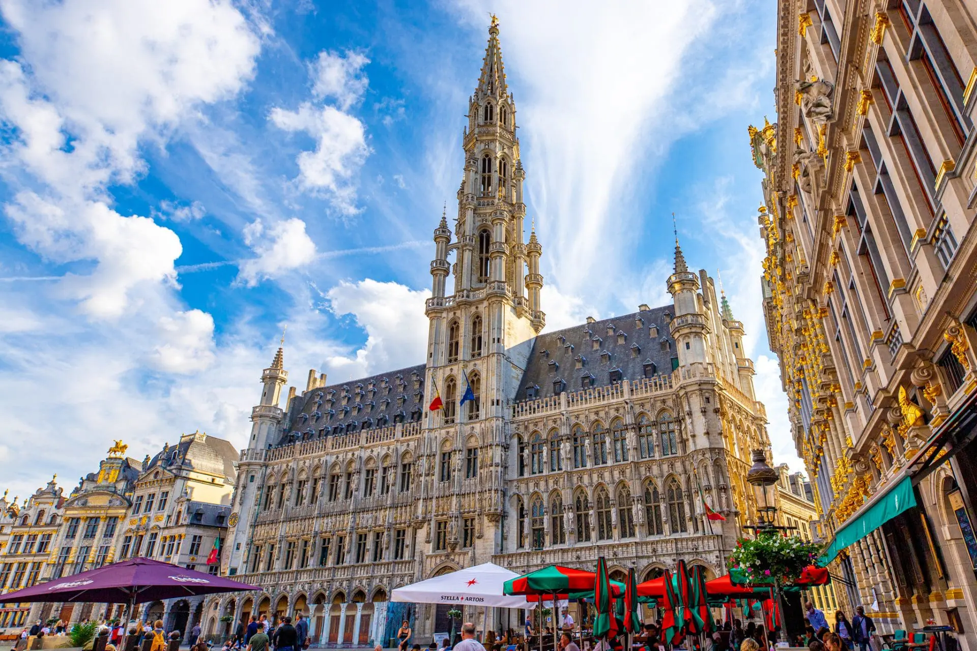 Photo of Brussels Town Hall with a tall spire and intricate architectural details under a blue sky. | Wander Sober