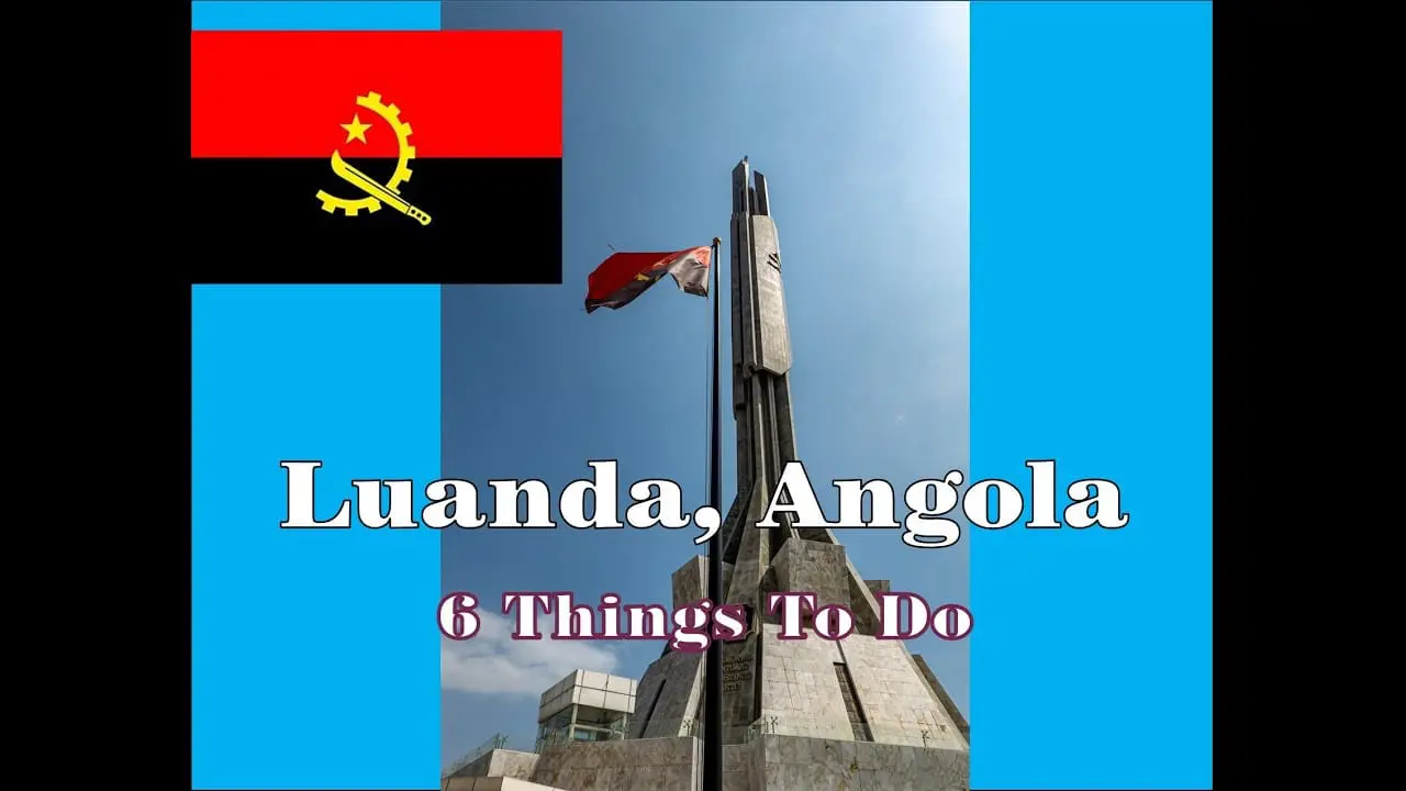 Photo of A prominent monument in Luanda, Angola, with flags displayed at its base and a blue background. | Wander Sober
