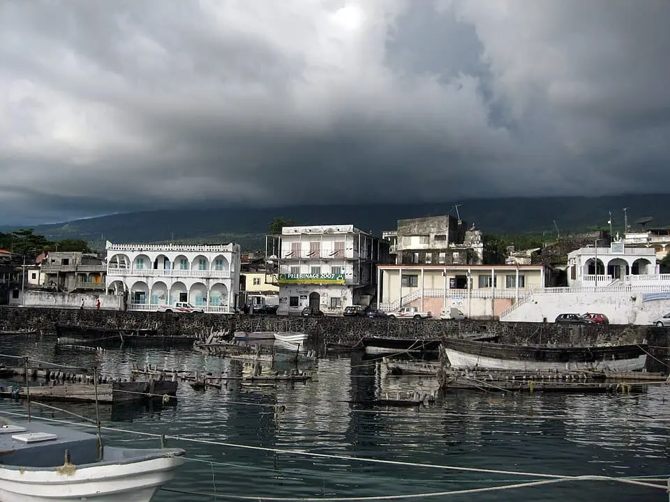 Photo of View of a harbor featuring buildings and boats under a cloudy sky. | Wander Sober