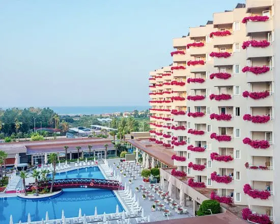 Photo of View of a hotel building with balconies adorned with flowers and a swimming pool in the foreground. | Wander Sober