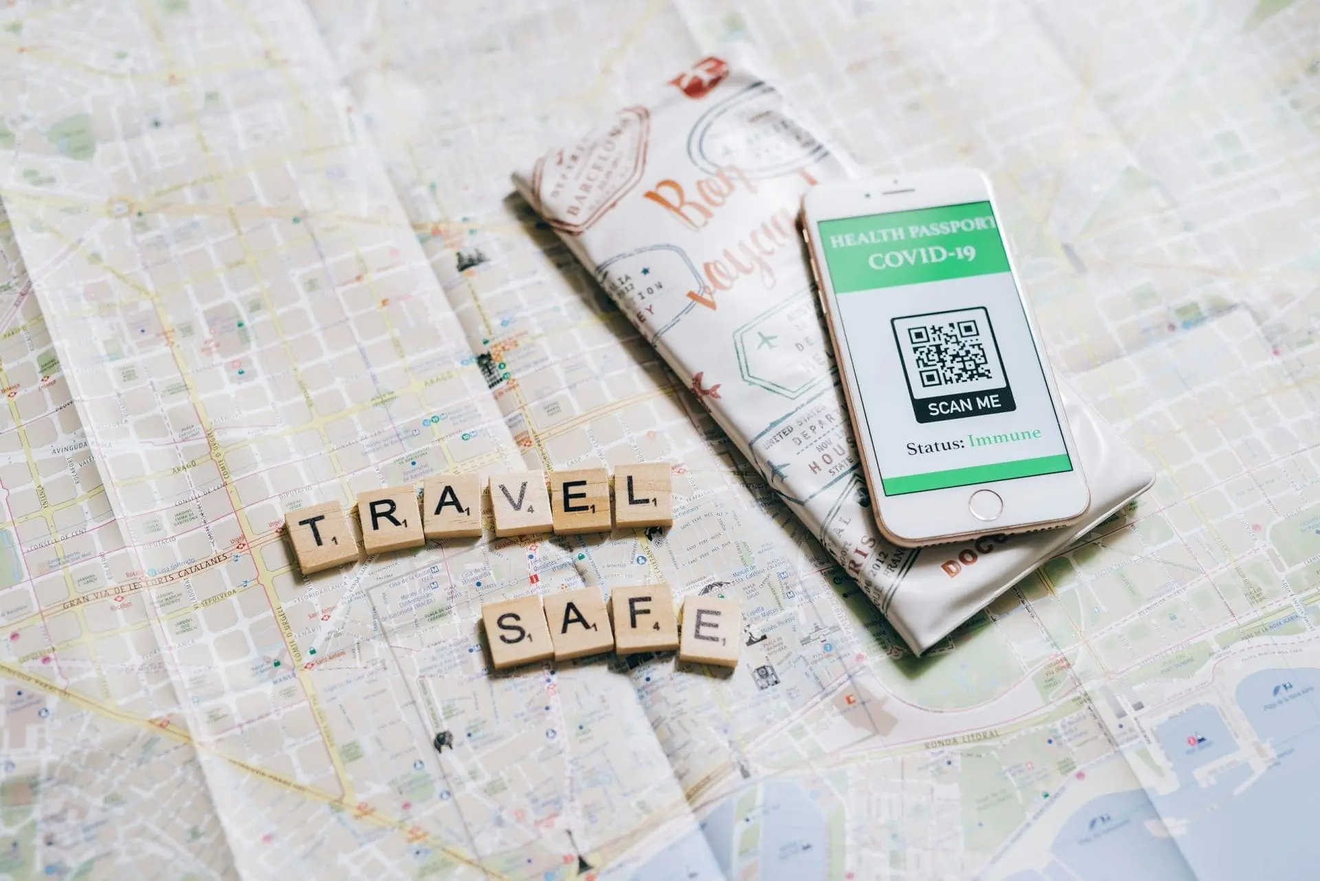 A smartphone displaying a COVID-19 health passport next to travel-themed items on a map.