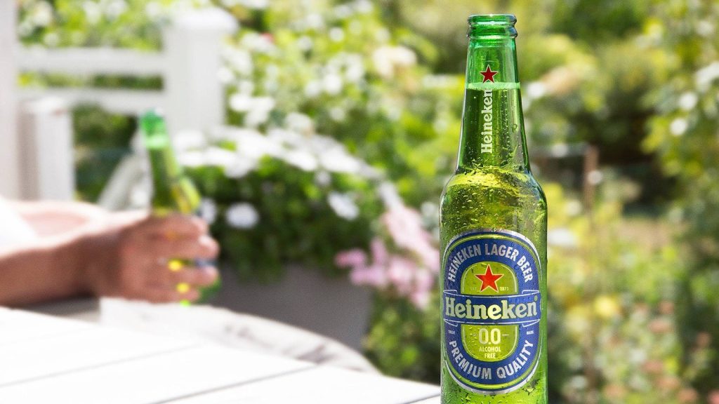 Photo of Green glass bottle of Heineken lager beer with a red star label on a table. | Wander Sober