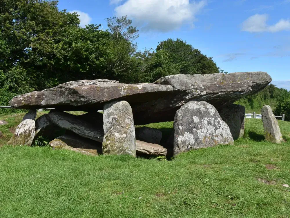 Ancient stone structure at King Arthur's Mound, surrounded by lush greenery, symbolizing Britain's legendary history.