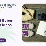 Sover Travel - A wooden surface with folded khaki pants, sunglasses, a vintage camera, an open notebook with a pencil, gray sneakers with purple laces, and a neck pillow. Text reads The Best Sober Travel Vacation Ideas with the Oasis Recovery Center logo. Perfect for your next mindful adventure!.